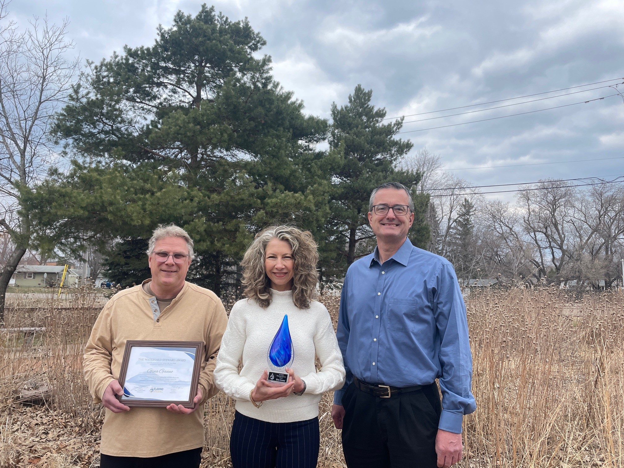 VLAWMO Board Chair Lindner, Watershed Steward Award Winner Gina Ganno Schmidt, and VLAWMO Administrator Phil Belfiori stand with the physical Watershed Steward Award.